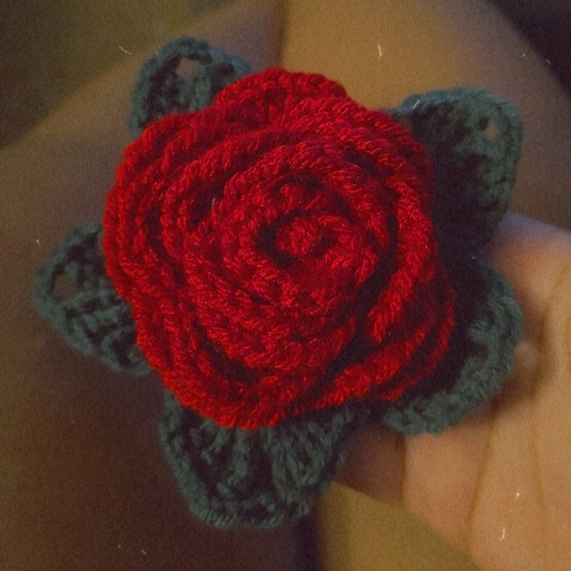Hand-crocheted red rose brooch with green leaves